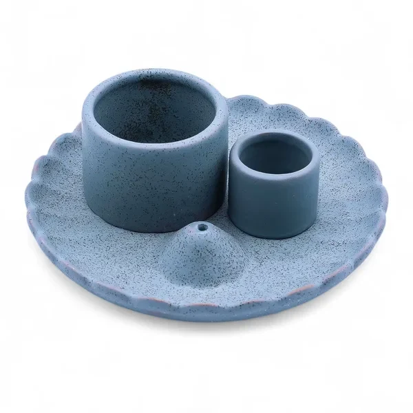 Ceramiczna niebieska podstawka w formie kwiatu lotosu z dwoma cylindrami na pęczki ziół oraz drewienka Palo Santo na ciemnym tle.