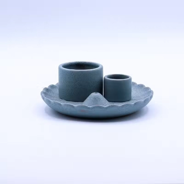Ceramiczna niebieska podstawka w formie kwiatu lotosu z dwoma cylindrami na pęczki ziół oraz drewienka Palo Santo na ciemnym tle.