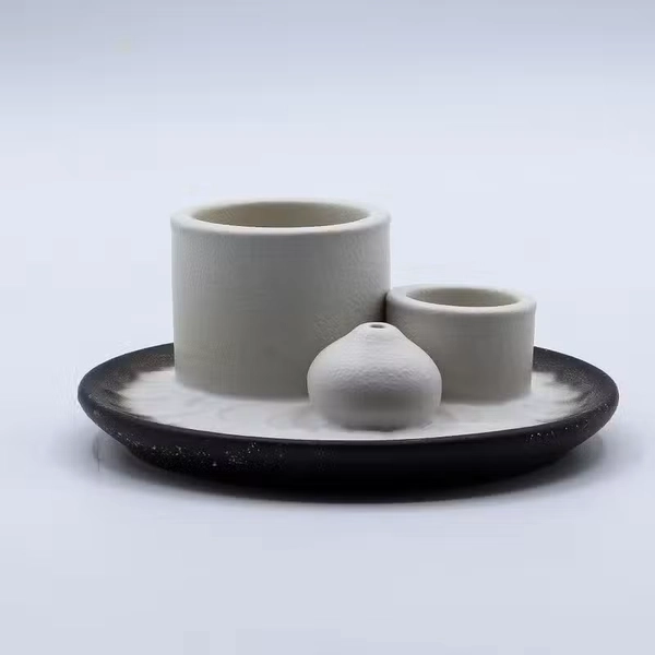 Nowoczesna ceramiczna podstawka z białymi cylindrami na Palo Santo i pęczki oraz ciemną misą z subtelnym motywem mandali.