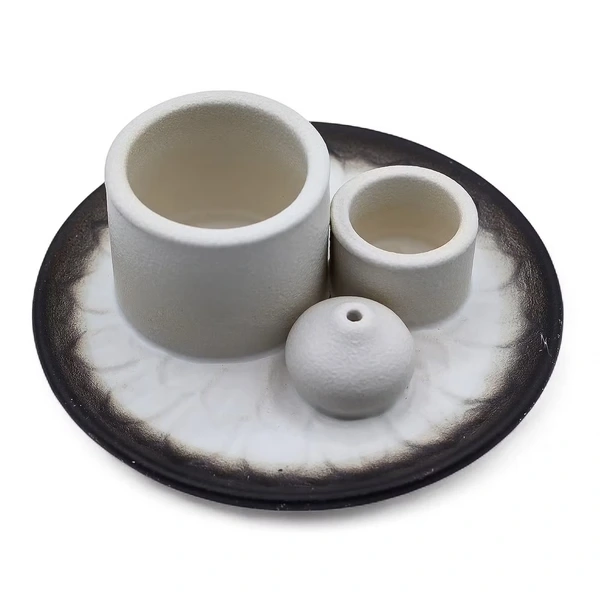 Nowoczesna ceramiczna podstawka z białymi cylindrami na Palo Santo i pęczki oraz ciemną misą z subtelnym motywem mandali.