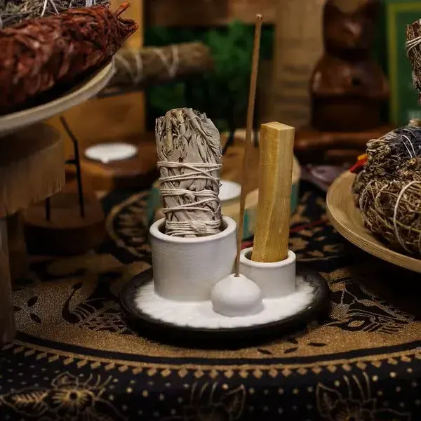 Nowoczesna ceramiczna podstawka z białymi cylindrami na Palo Santo i pęczki oraz ciemną misą z subtelnym motywem mandali.