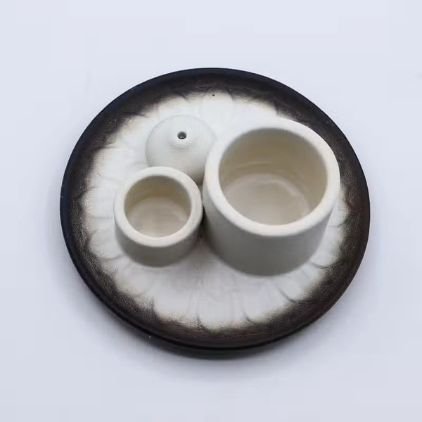 Nowoczesna ceramiczna podstawka z białymi cylindrami na Palo Santo i pęczki oraz ciemną misą z subtelnym motywem mandali.