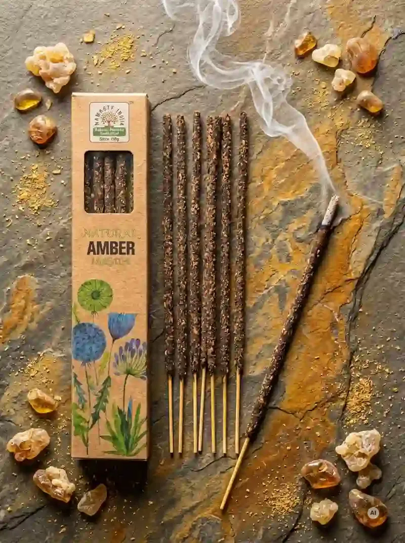 Ekologiczne pudełeczko kadzidełek Namaste India Amber Bursztyn obok ułożonych patyczków masala obsypanych aromatycznym pyłkiem żywicznym.