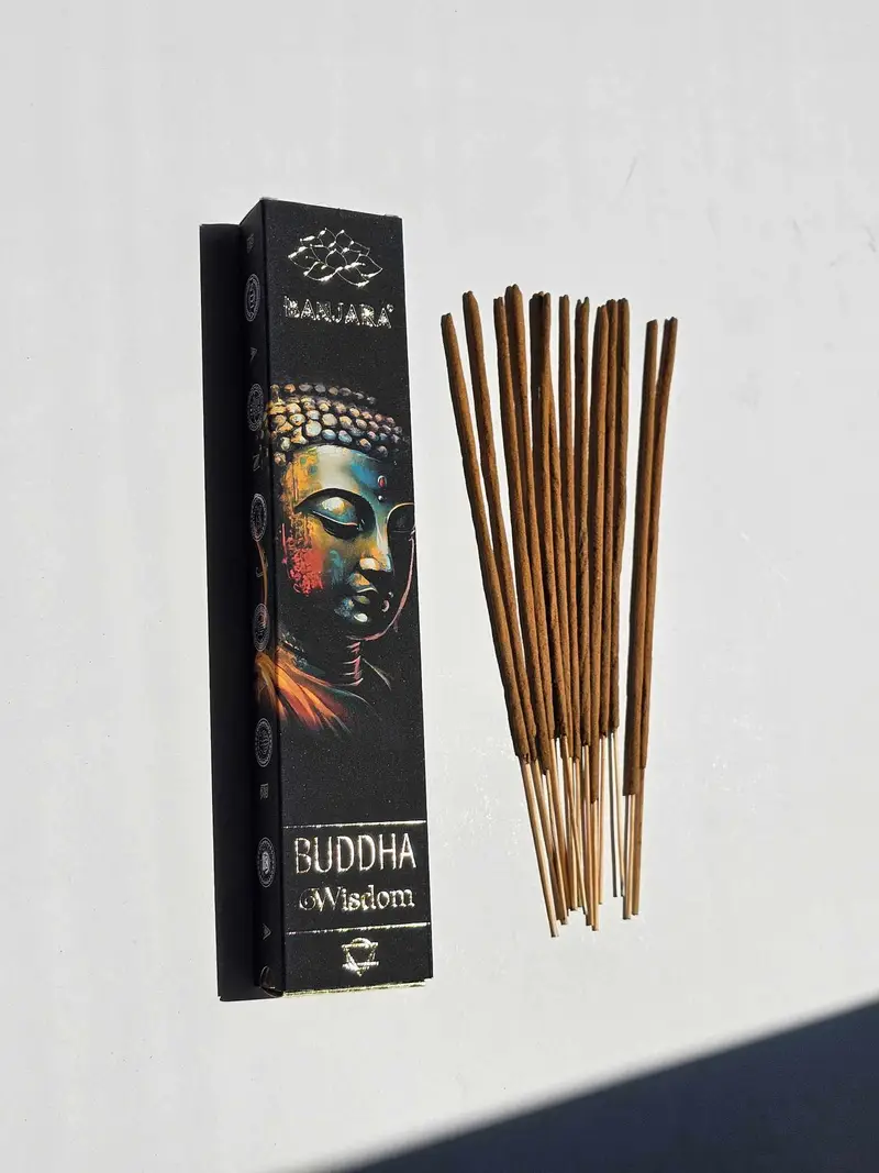 Oryginalne butelkowozielone opakowanie kadzidełek BANJARA Buddha Wisdom ze złotym posągiem Buddy obok naturalnych patyczków masala.