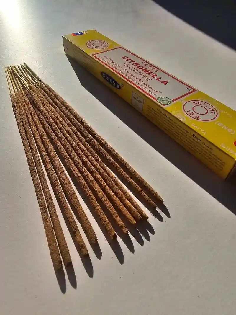 Oryginalne żółto kremowe opakowanie indyjskich kadzidełek SATYA Citronella obok naturalnych patyczków masala.