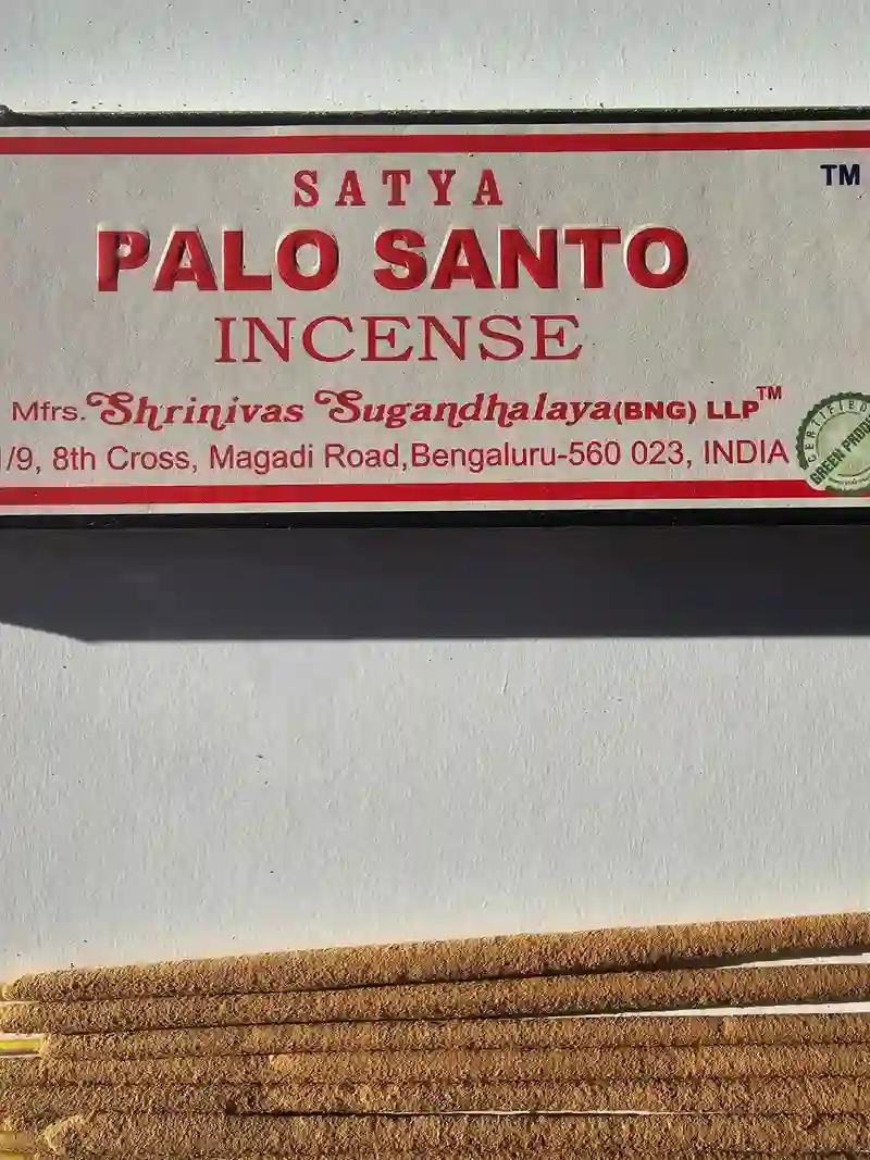 Oryginalne granatowo kremowe opakowanie indyjskich kadzidełek SATYA Palo Santo obok naturalnych patyczków masala.