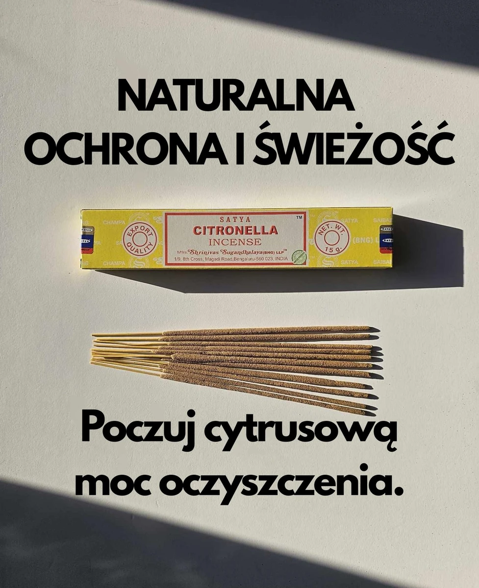 Jasnożółte pudełko kadzideł Satya Citronella 15g ułożone poziomo nad grupą jasnobrązowych patyczków na białym tle z wyraźnym cieniem.