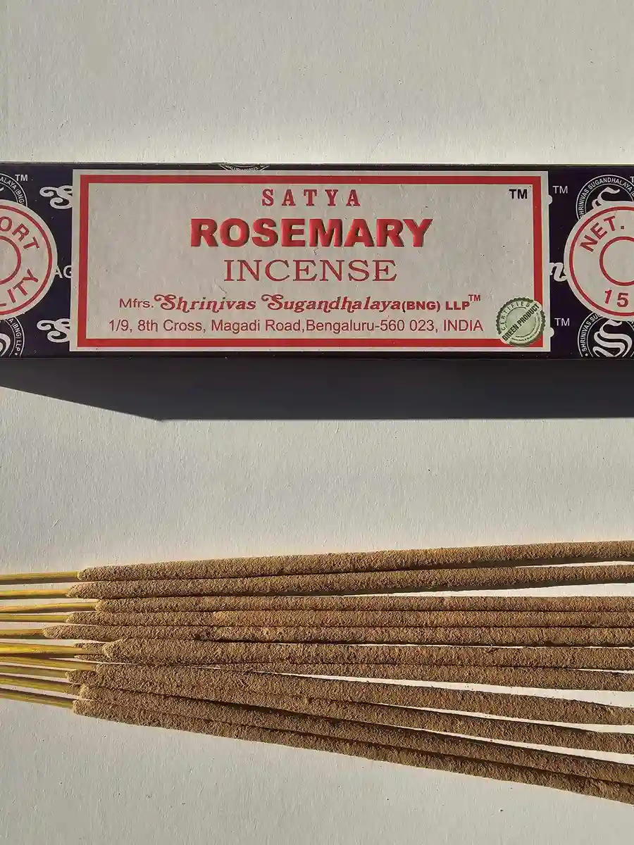 Ciemnofioletowe pudełko kadzideł Satya Rosemary 15g leżące poziomo nad stosem jasnobrązowych patyczków na białym tle z mocnym cieniem rzucanym w prawą stronę.