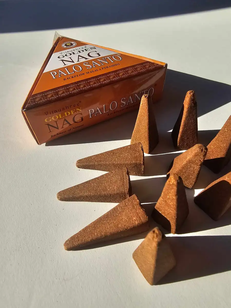Stożkowe kadzidełka backflow Golden Nag Palo Santo ułożone w artystyczny sposób, prezentujące rozwiązanie dla osób pragnących zamienić zwykły wieczór w magiczny rytuał.