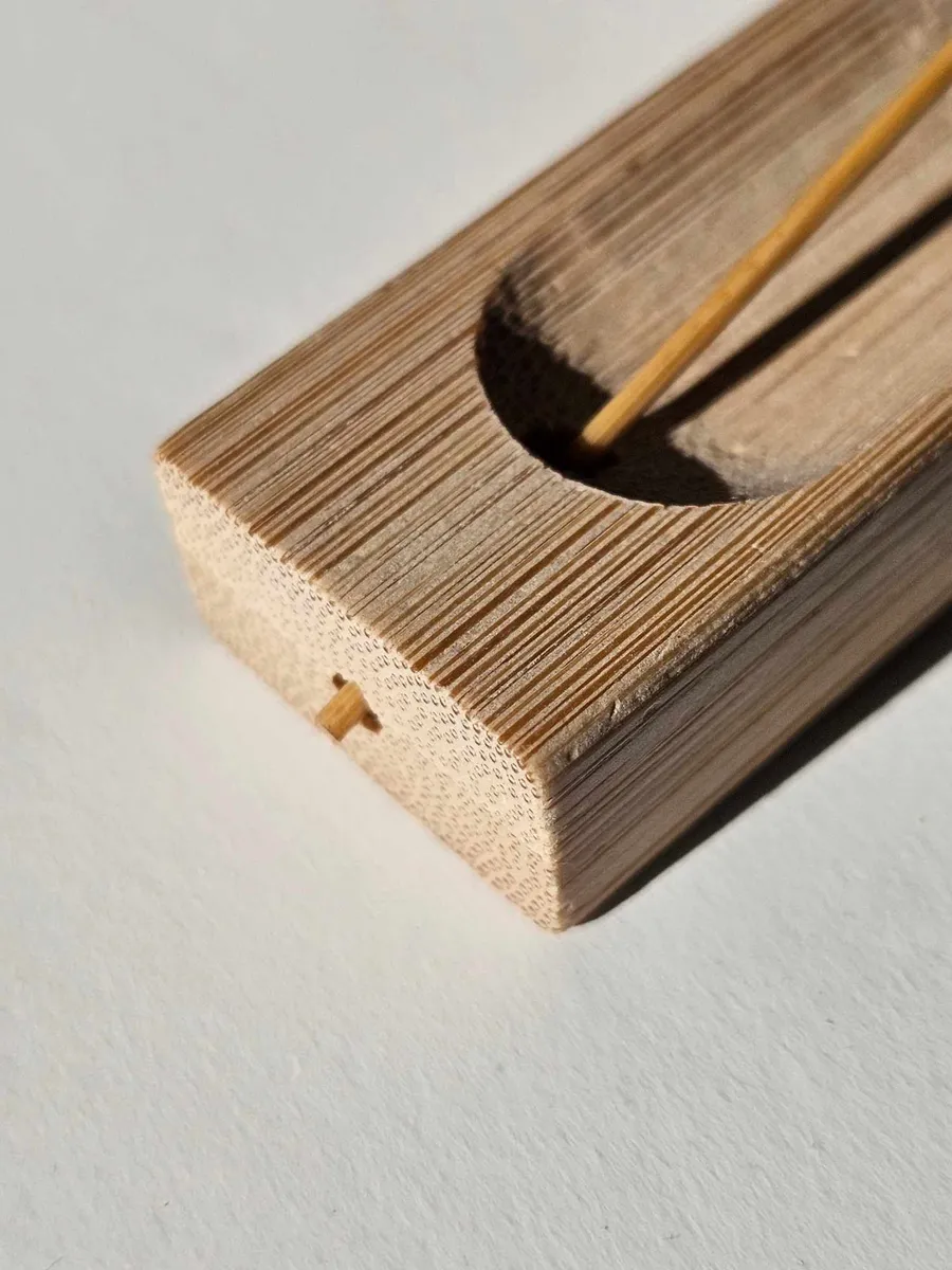Wąska bambusowa podstawka typu korytko z zapalonym kadzidłem, umieszczona na jasnym blacie, podkreślająca minimalistyczny design.