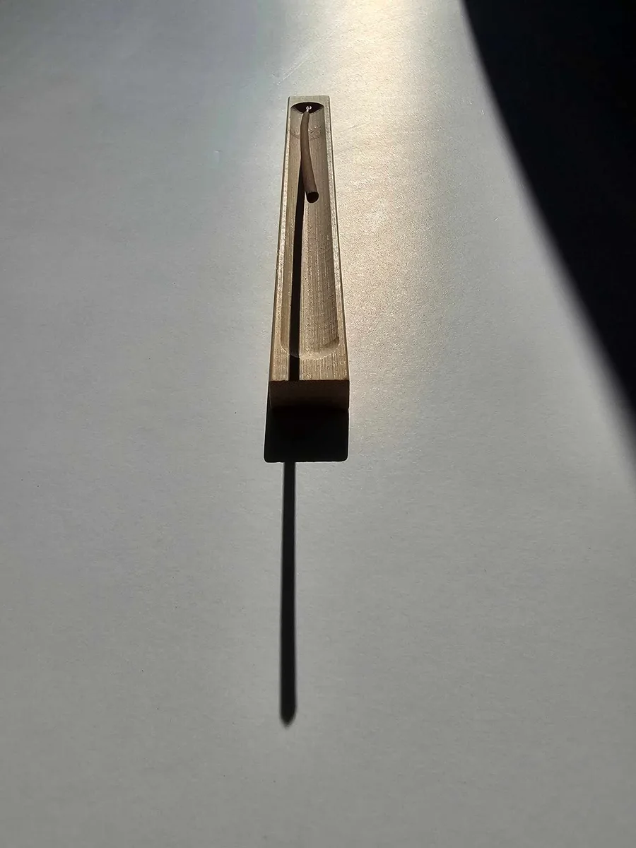 Wąska bambusowa podstawka typu korytko z zapalonym kadzidłem, umieszczona na jasnym blacie, podkreślająca minimalistyczny design.