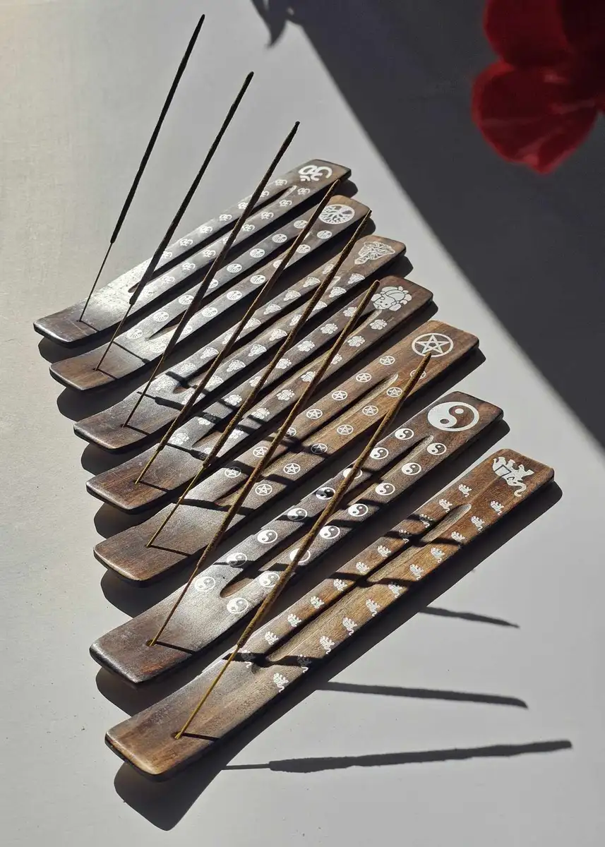 Zestaw drewnianych podstawek typu narta w ciemnym kolorze z różnymi białymi zdobieniami (Om, drzewo życia, yin-yang), prezentujący różnorodność dostępnych wzorów.