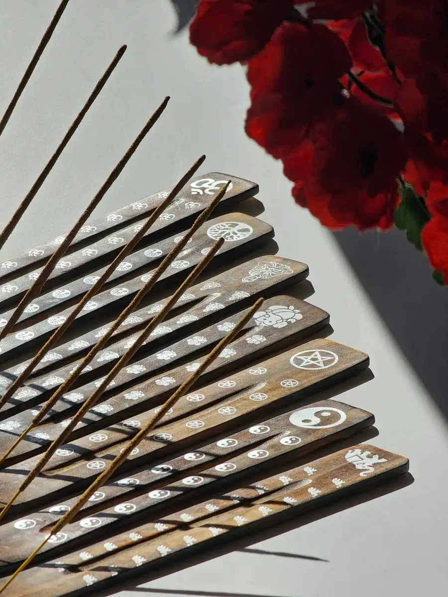 Zestaw drewnianych podstawek typu narta w ciemnym kolorze z różnymi białymi zdobieniami (Om, drzewo życia, yin-yang), prezentujący różnorodność dostępnych wzorów.