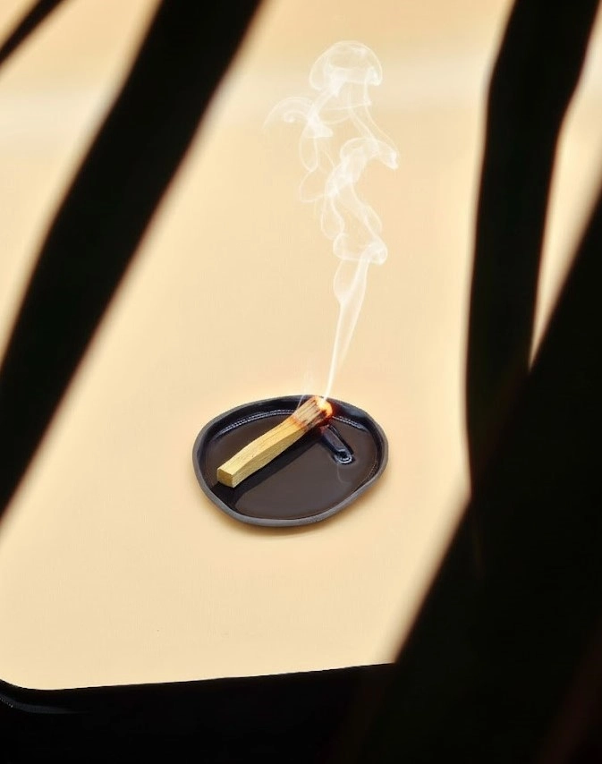 Okrągła ceramiczna podstawka w głębokim kobaltowym odcieniu, wykonana ręcznie w Krakowie, prezentująca bezpieczne użycie z Palo Santo.